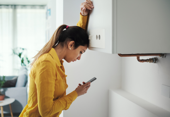Worried woman calling a boiler breakdown emergency service using her smartphone