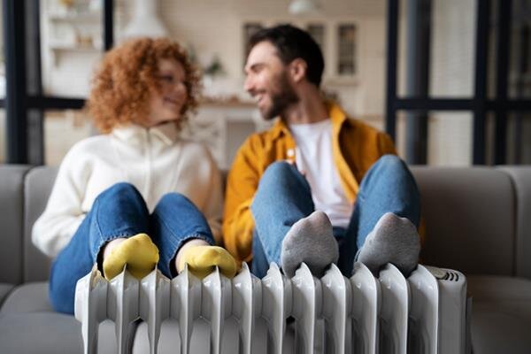 smiley couple warming up near heater