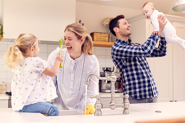 Family having fun in kitchen doing washing up at sink together