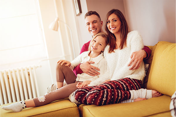 Happy family relaxing on a sofa near a home radiator in a warm living room