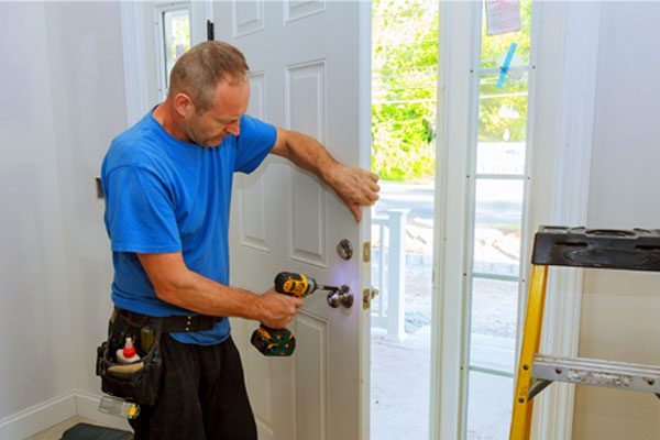 Handyman installing a new door lock with a drill