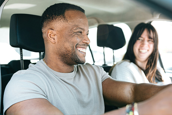 Man in the driver’s seat with a woman in the passenger seat, both smiling